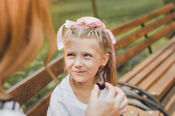 Blue-eyed cute girl tasting sweet candy in the park — Stock Photo, Image