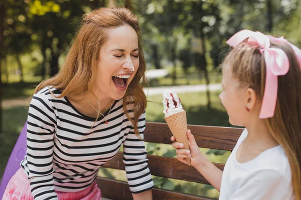 Blonde-haired funny girl eating ice cream with her mother