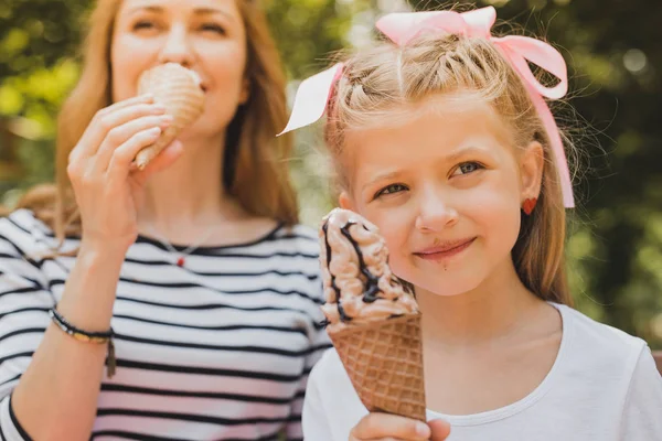 Blonde-haired daughter with cute hair style eating ice cream