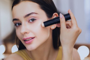 Sevimli kadın makyaj koyarak süre kapatıcı stick kullanarak