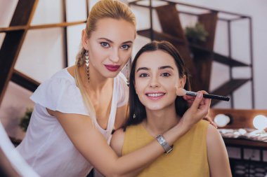 Koyu renk saçlı gülen kadın makyaj sanatçısı konuşmak zevk