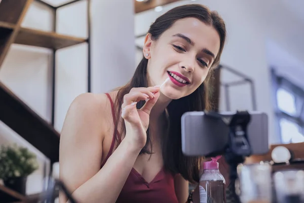 Femme gaie aux cheveux foncés fixant son maquillage — Photo