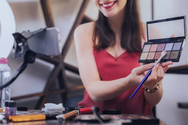 Blogueiro de beleza sorridente filmando vídeo sobre cores de sombras de olhos — Fotografia de Stock