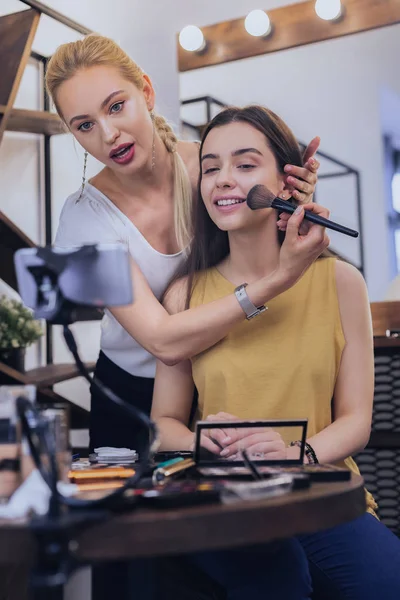 Blogger de beleza loira mostrando segredos de maquiagem em seu modelo — Fotografia de Stock