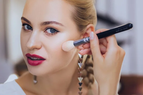 Mujer de cabello rubio con labios rojos sosteniendo cepillo de maquillaje — Foto de Stock