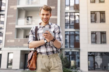 Onun akıllı telefon ekranına bakarak mutlu neşeli adam