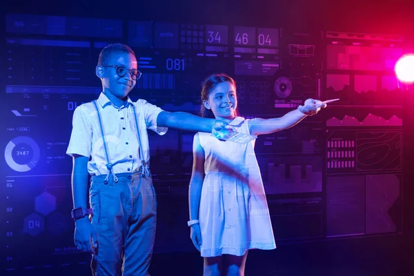 Χαμογελαστό αγόρι στέκεται με ένα χαρούμενο κορίτσι και εκμετάλλευση σύγχρονων συσκευών — Φωτογραφία Αρχείου