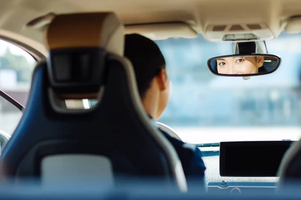 Nice pleasant woman looking in the rearview mirror — Stock Photo, Image