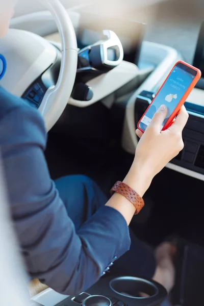 Cierre de un teléfono inteligente que es la ayuda del conductor femenino — Foto de Stock