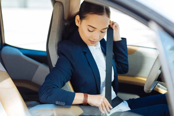 Nice serious woman looking at her seatbelt — Stock Photo, Image