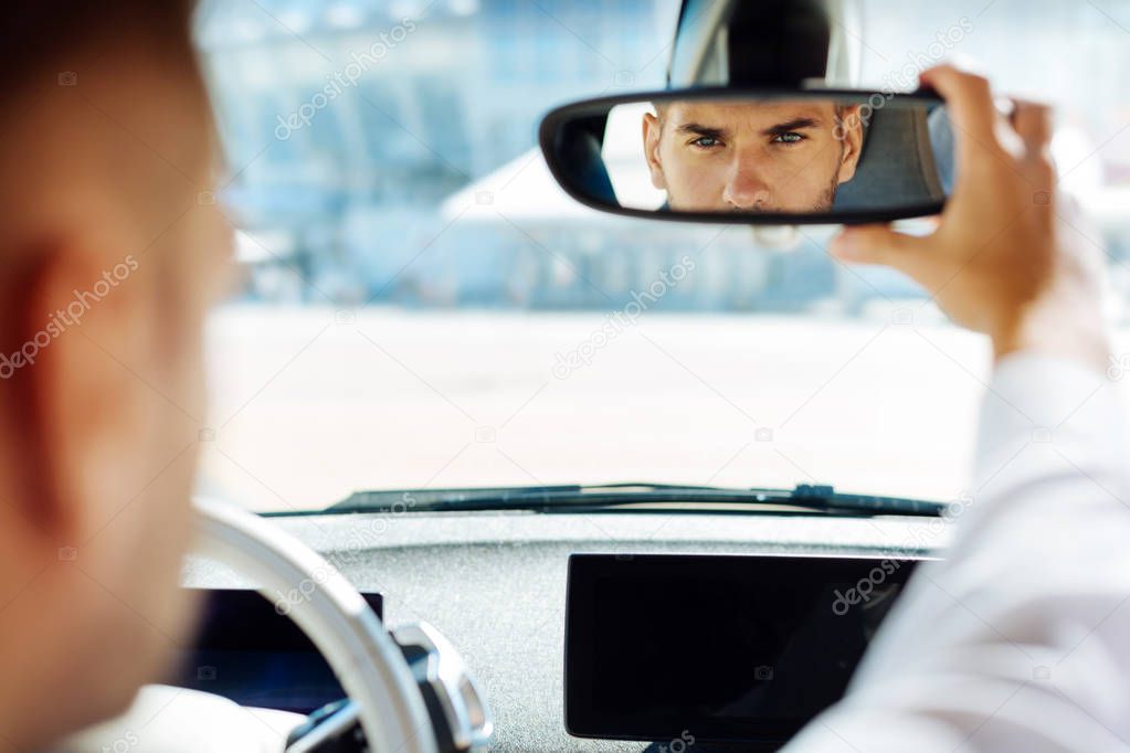 Confident smart man looking into the rearview mirror