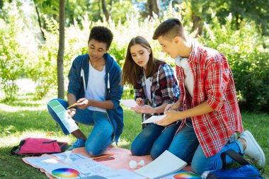 Sanat öğrencileri farklı renk tonları için yaklaşan tasarımlarını bakıyor