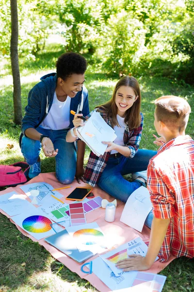 Drei positiv lächelnde Studenten verbringen ihre Zeit in der Natur — Stockfoto