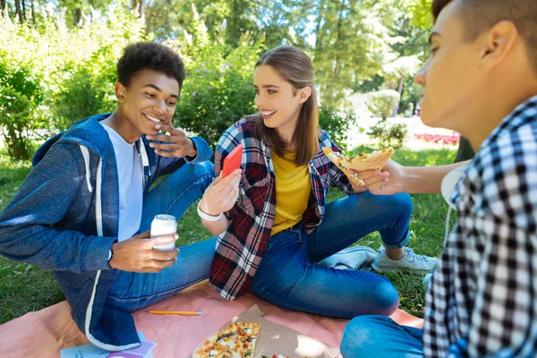 Трое друзей в джинсах едят вкусную пиццу вместе — стоковое фото