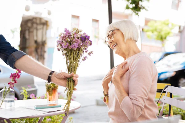 Schöne Seniorin nimmt Blumenstrauß — Stockfoto