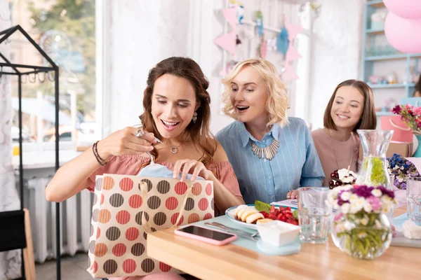 Mörkhårig förskottsbetalande kvinna känsla upphetsad samtidigt uppackning närvarande — Stockfoto