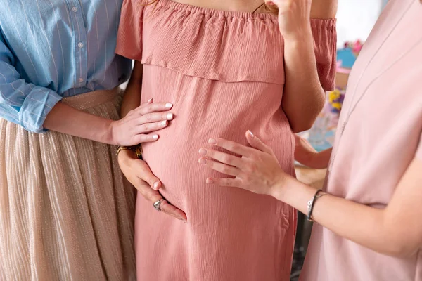 Две стильные женщины с красивыми ногтями трогают беременный животик — стоковое фото