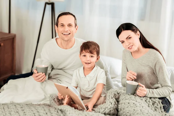 Счастливая счастливая семья отдыхает в постели — стоковое фото