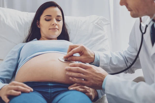 Gåtfulla ung kvinna tittar på hennes baby bump — Stockfoto