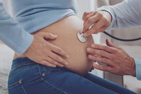 Fechar as mãos femininas que abraçam sua barriga — Fotografia de Stock