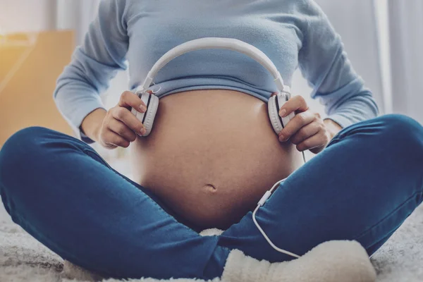 Gros plan de la femme enceinte qui tient des écouteurs — Photo