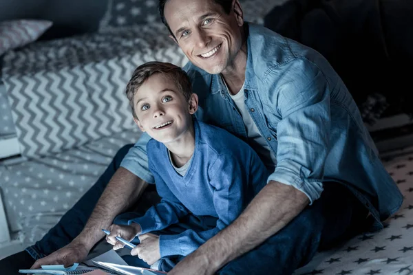 Pai alegre sentado perto de seu filho — Fotografia de Stock