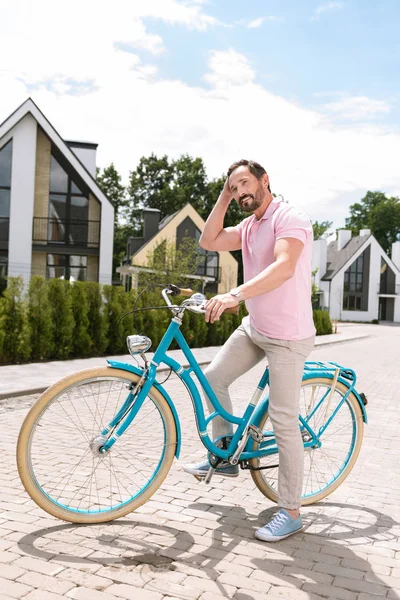 Hombre positivo alegre de pie con su bicicleta — Foto de Stock