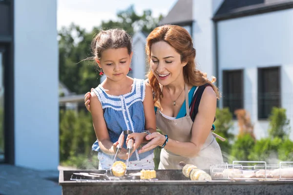 Örömteli, szép anya és lánya, grillezés, kukorica — Stock Fotó