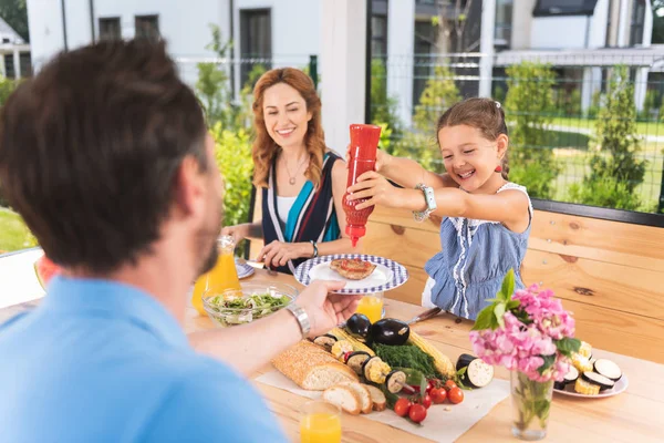 Aranyos pozitív girl gazdaság egy palackot, ketchup — Stock Fotó