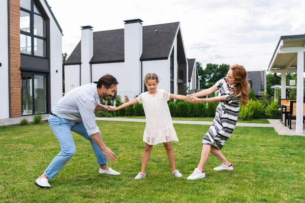 Agradable linda chica de pie entre sus padres — Foto de Stock