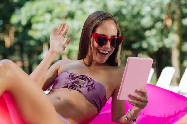 Mulher que transmite vídeo chat enquanto nada na piscina — Fotografia de Stock