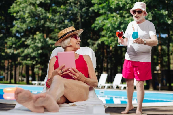 Elegante donna che indossa cappello di paglia prendere il sole vicino alla piscina — Foto Stock