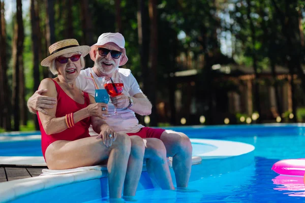 Casal sorridente de pensionistas sentados perto da piscina exterior — Fotografia de Stock