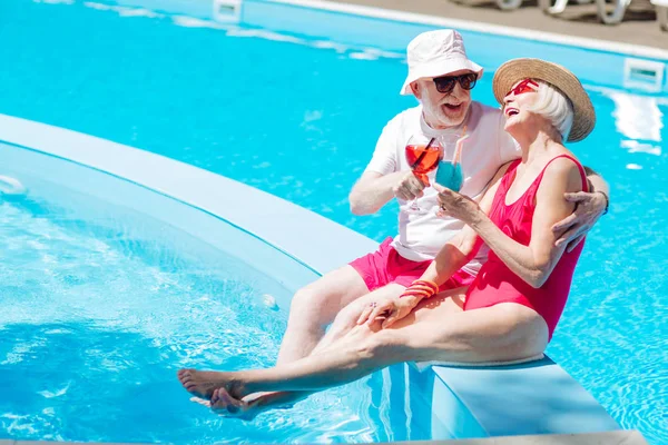 Homme et femme à la retraite riant en bronzant près de la piscine — Photo