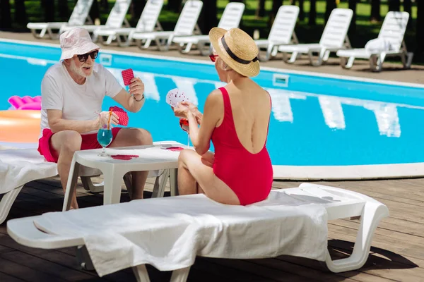 Femme retraitée mince portant un maillot de bain rouge jouant aux cartes — Photo