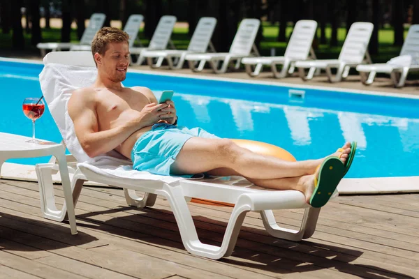 Prosperous businessman chilling while sunbathing near pool — Stock Photo, Image