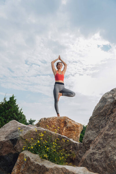 Dark-haired woman smiling while doing yoga on weekend morning