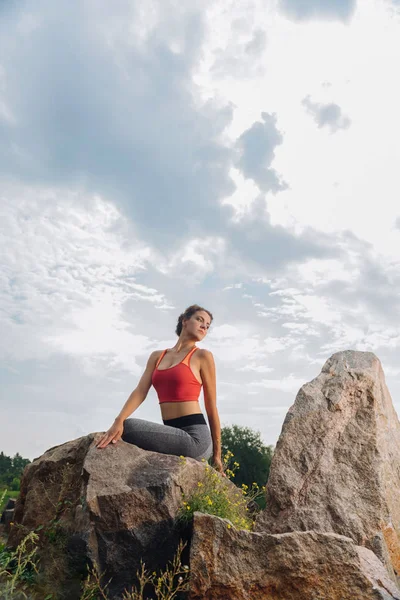 Mujer disfrutando del aire fresco mientras se estira cerca de las rocas — Foto de Stock