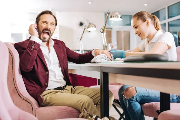 Glad female manicurist taking care of male hands — Stock Photo, Image