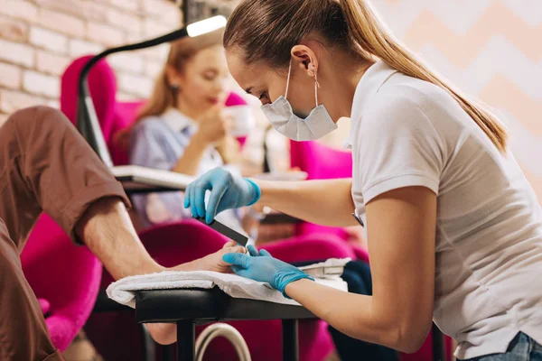 Successful female manicurist filing nails on foot — Stock Photo, Image