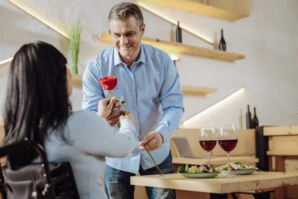 Homem alegre apresentando uma flor a uma mulher — Fotografia de Stock