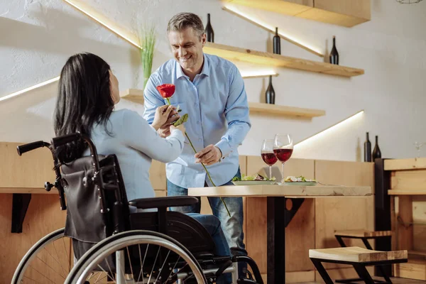 Homem atraente apresentando uma rosa para uma mulher com deficiência — Fotografia de Stock