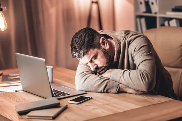 Homem de negócios cansado deitado na mesa em frente ao laptop — Fotografia de Stock