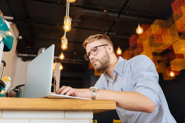 Vousatý stylový muž na sobě pruhované tričko, pracuje na jeho laptopu — Stock fotografie