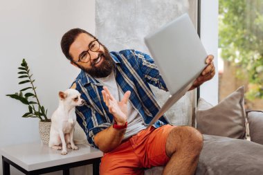 Köpeğin yanına oturan görüntülü sohbet sahip esmer gülen adam