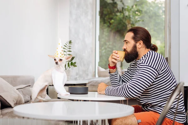 Hombre moreno con pantalones cortos rojos bebiendo sabroso café con leche — Foto de Stock