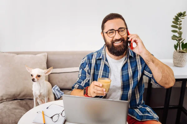 Smiling bearded man calling his business partner drinking coffee