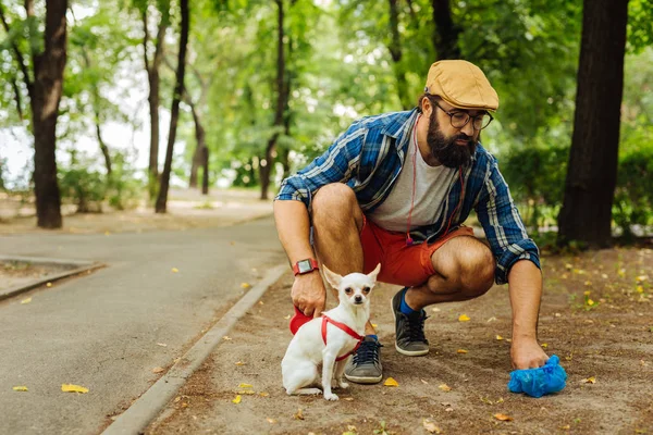 Bearded man wearing glasses taking care of his dog