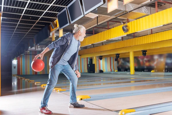 Homem velho barbudo agradável jogando boliche fervorosamente — Fotografia de Stock