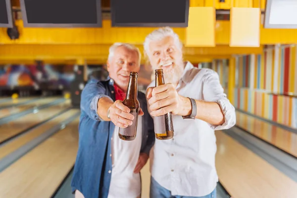 Selective focus of bottles of beer in hands of elderly men — Stock Photo, Image